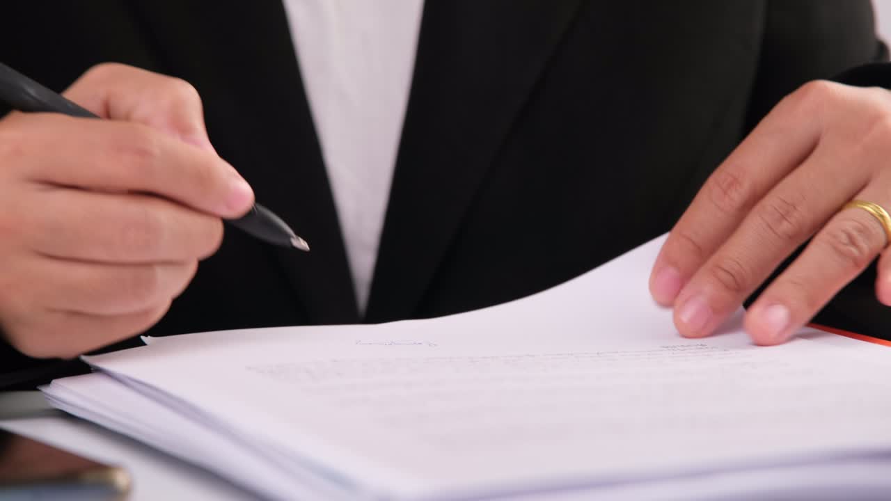 un primer plano de las manos de una mujer de negocios escribiendo un documento de negocios en el lugar de trabajo.
