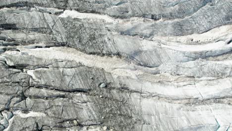 de arriba hacia abajo, vuelo aéreo cercano sobre el glaciar de hielo con grietas y grietas negras profundas, concepto de fusión del glaciar del calentamiento global, sobrevuelo aéreo de allalingletscher suiza