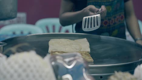 man-in-apron-cooks-food-with-golden-crust-in-frying-pan