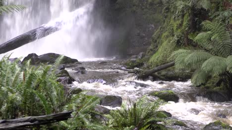 Close-up-of-rocky-river-stream-with-waterfall-flowing-and-falling-onto-log