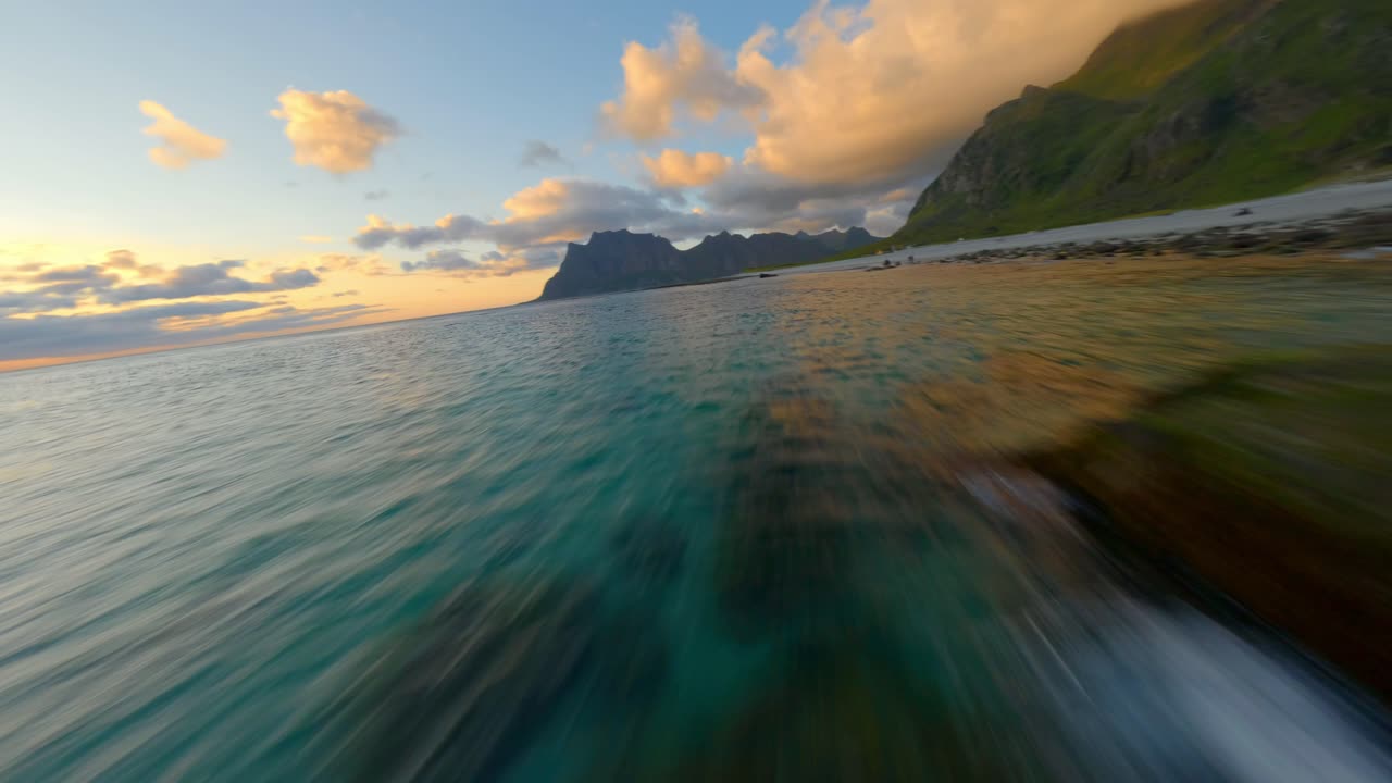 Fpv fast flight along Lofoten beach and clear water with rocks during golden Sunset in Norway - Low angle flight
