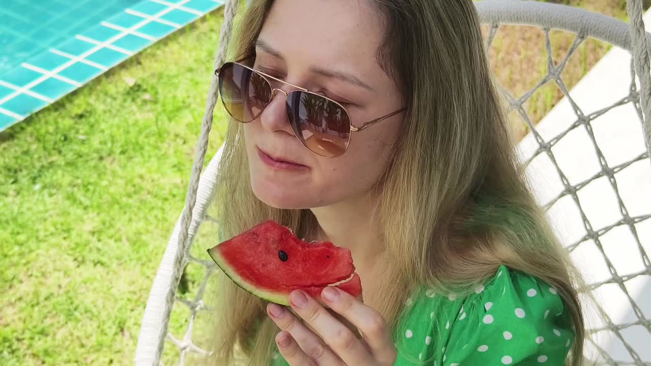 mujer comiendo sandía junto a una piscina