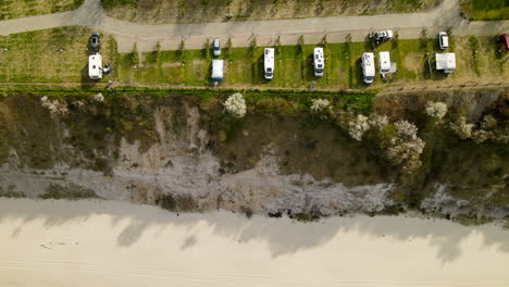 aerial view of chlapowo campsite with many camper trailers parked on a cliff beach front of baltic sea, poland travel spot