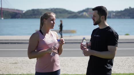 sporty young people drinking water from plastic bottles.