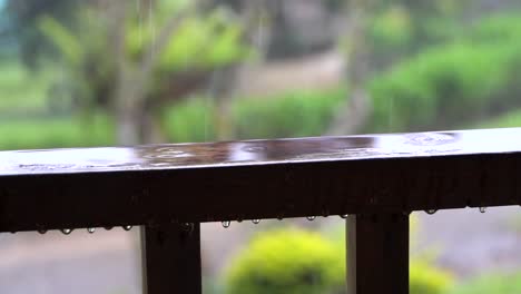 Slow-motion-raindrops-splash-onto-wet-wooden-railing,-rain-background
