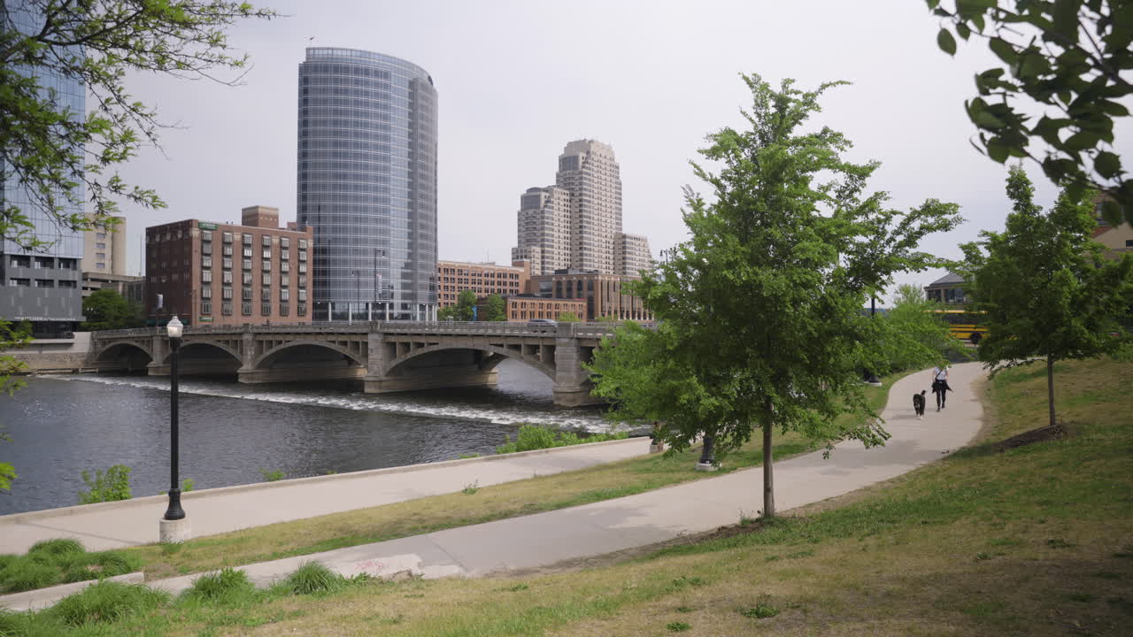 mujer joven caminando con su perro por un camino pavimentado en un entorno urbano