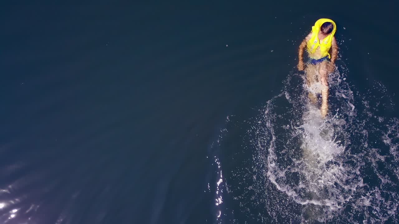 Boy having fun in river. Top down view of happy boy having fun, swimming in the river water