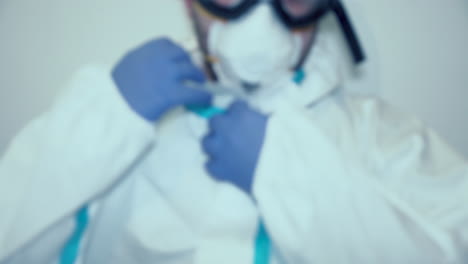 retrato recortado de un trabajador médico poniéndose la capucha del traje de ppe - concepto de coronavirus - plano medio