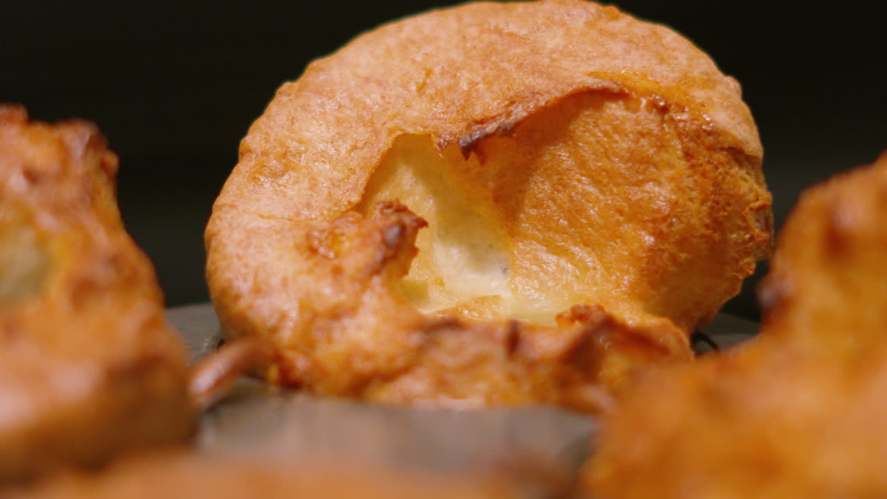 Pequeños Puddings de Yorkshire británicos dorados, recién cocinados, con textura crujiente por fuera y suaves por dentro. Gastronomía inglesa ideal para promocionar comidas familiares, menús de pub y contenido relacionado