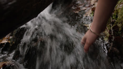 hands touching water in running stream