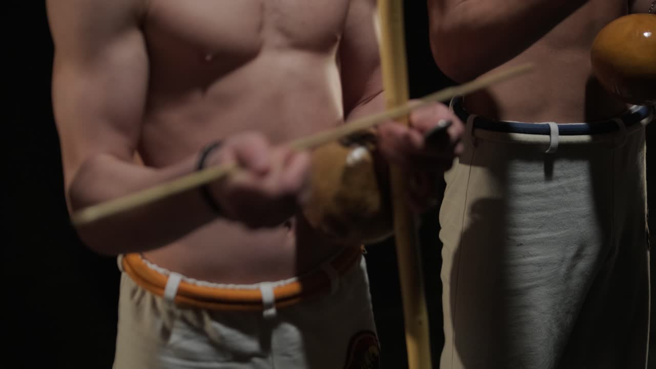 프로 댄서 그룹이 어 속에서 카포에이라를 연습하고 있으며, 스튜디오의 검은 바탕에 스포트라이트가 있습니다. 댄스의 요소를 결합하는 아프리카-브라질 무술입니다.