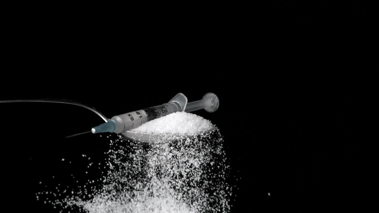 Needle falling onto spoon full of sugar on black background