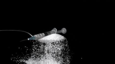 Needle-falling-onto-spoon-full-of-sugar-on-black-background