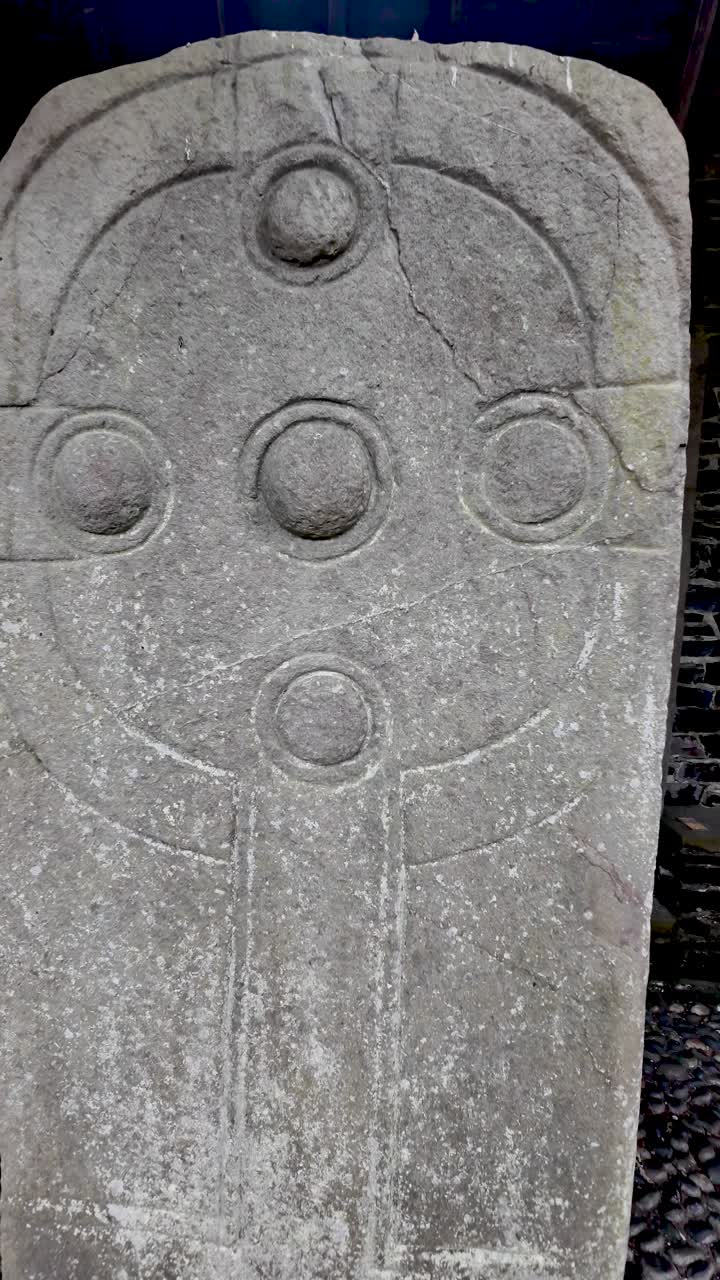 Ancient Manx cross featuring intricate Celtic carving standing inside a historical site