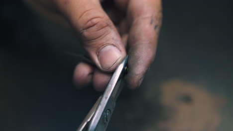 skilled jeweler cuts parts from spiral at workplace closeup