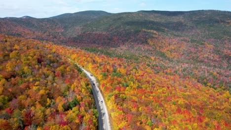 cars driving mountain pass in new england during fall with changing leaves