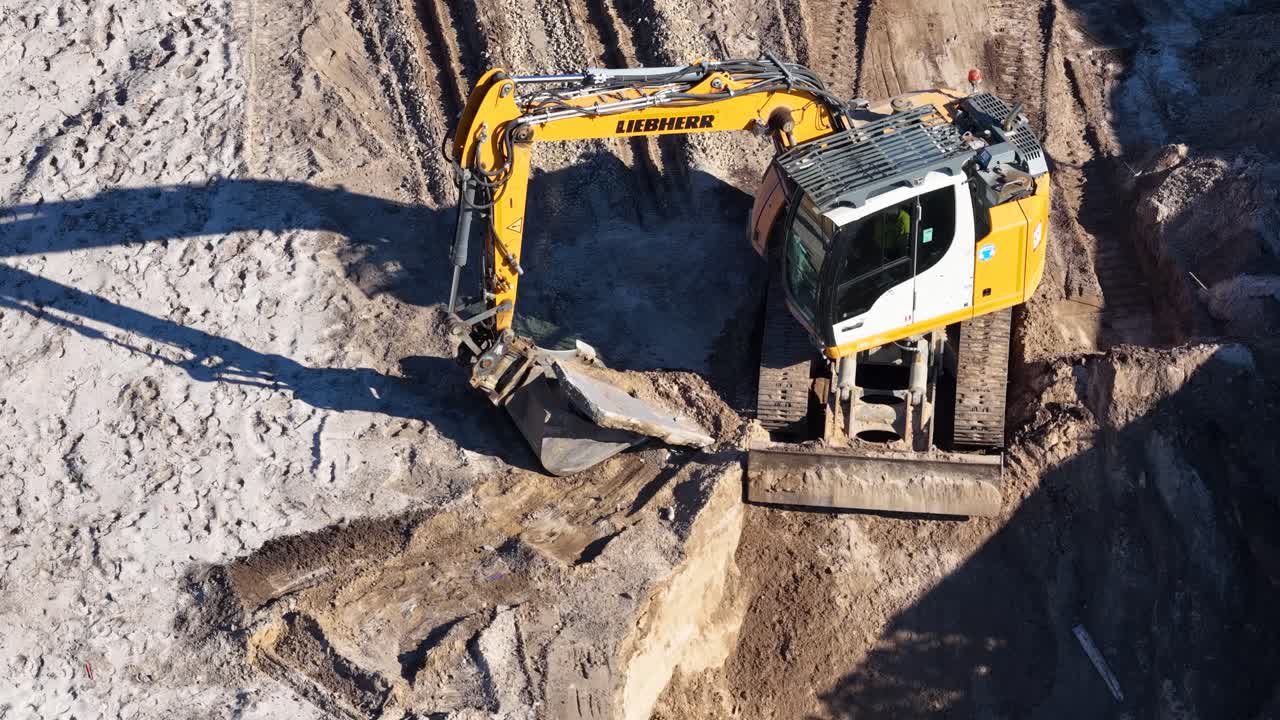 Excavator operates in sunlight, digging and relocating earth at Broadbeach Waters construction site