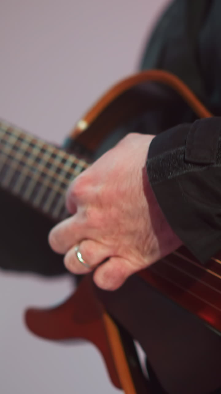 primer plano de la mano de un guitarrista tocando hábilmente una guitarra roja, con un fondo gris suavemente borroso que mejora el enfoque en la expresión musical