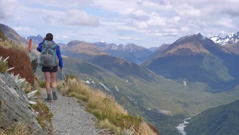 excursionista camina estática, pista alpina ventosa expuesta, valles distantes, routeburn track nueva zelanda