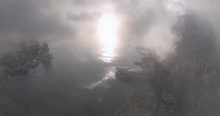 Drone shot through fog, toward the Convention and Exhibition Centre of Hong Kong
