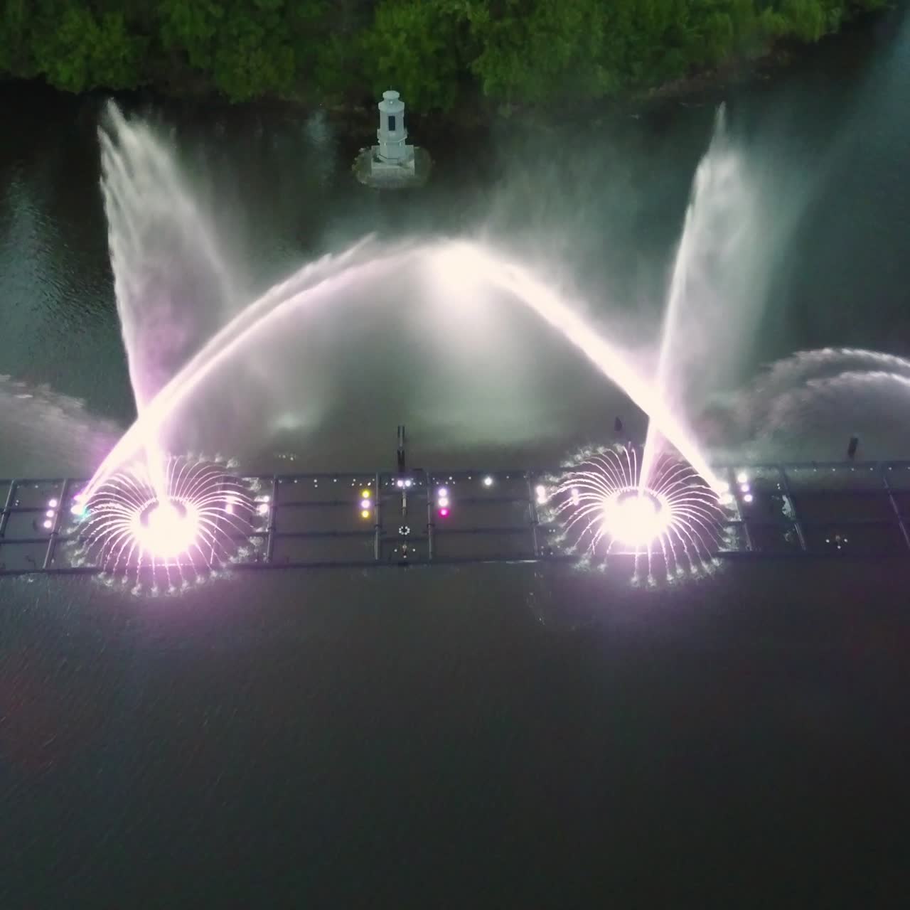 Water Music Fountain In Night. Aerial shot of the dancing colorful fountain with reflection on water at night