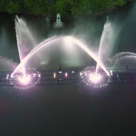 water music fountain in night. aerial shot of the dancing colorful fountain with reflection on water at night