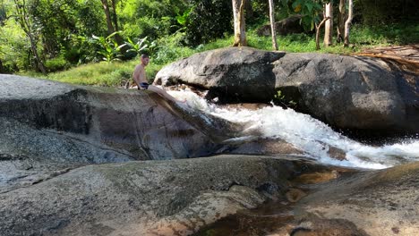 Un-Niño-Se-Desliza-Por-Una-Cascada-En-Pai,-Tailandia