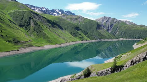 Reflejo-Del-Agua-En-El-Lago-De-Montaña-Lac-De-Grand-Maison-En-Los-Alpes-Franceses---Dolly-Aéreo-Hacia-Adelante