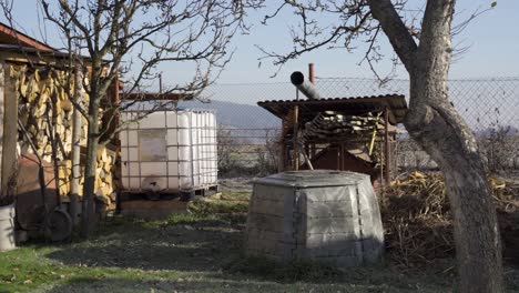 Left-to-right-pan-over-small-rural-garden-and-yard-during-bright-day