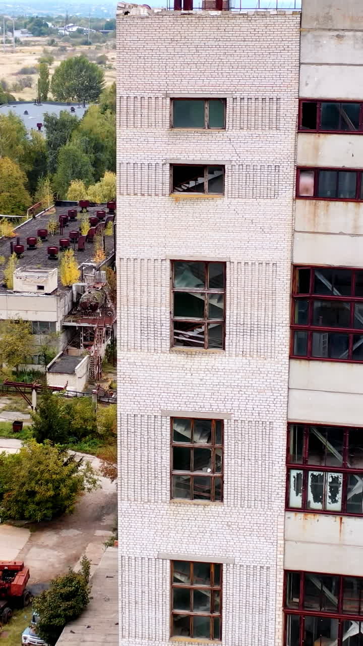 Tall building with broken windows and roof. Exterior of an old abandoned building on empty manufacturing. Damaged house.. Vertical video