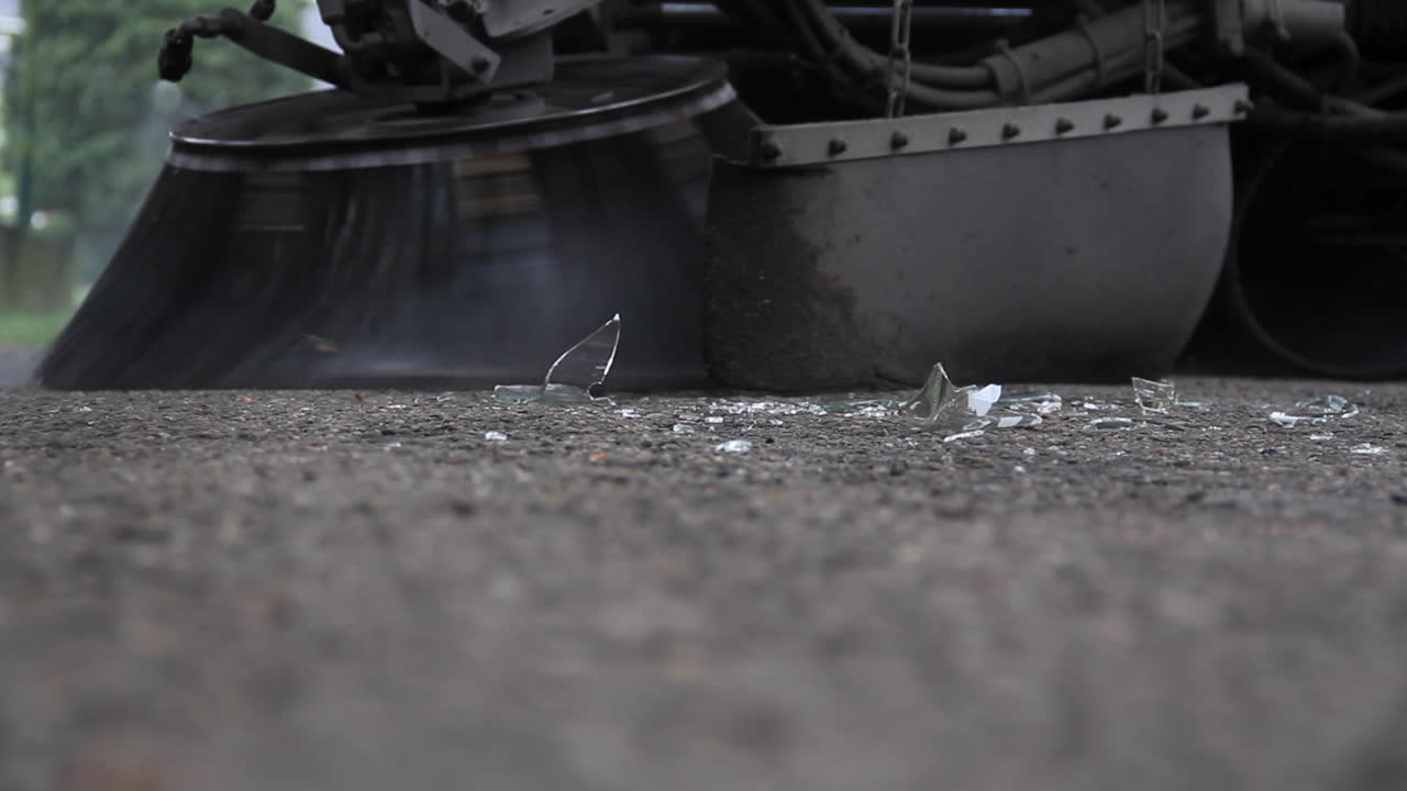 도로에 깨진 유리를 청소하는 거리 청소부