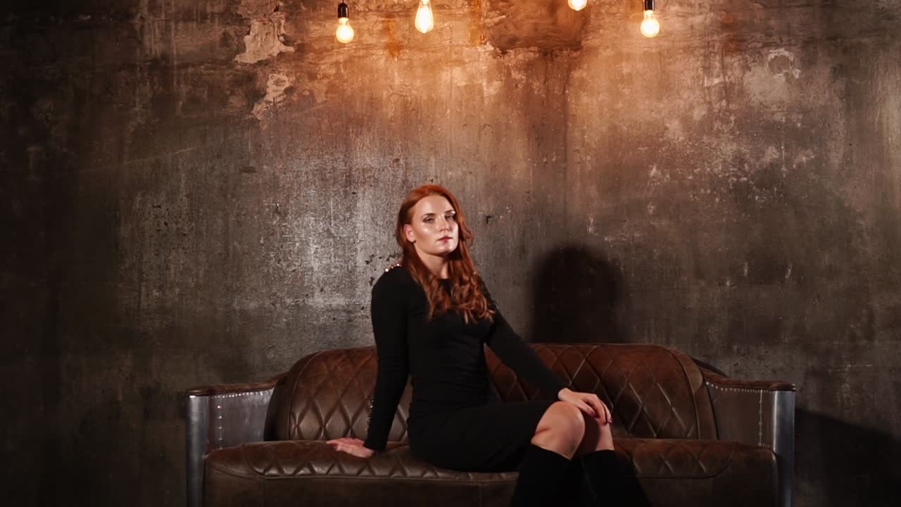 mujer en un vestido negro en un sofá de cuero