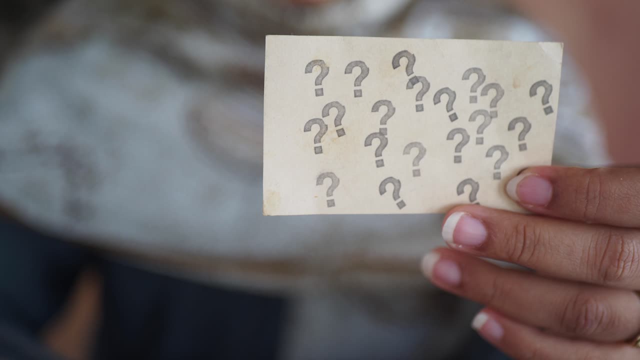 mujer sosteniendo una tarjeta con signos de interrogación