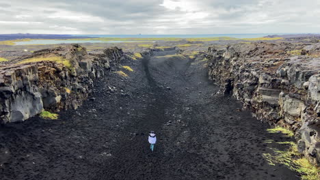 woman walking on epic path between american and eurasian tectonic plates, iceland