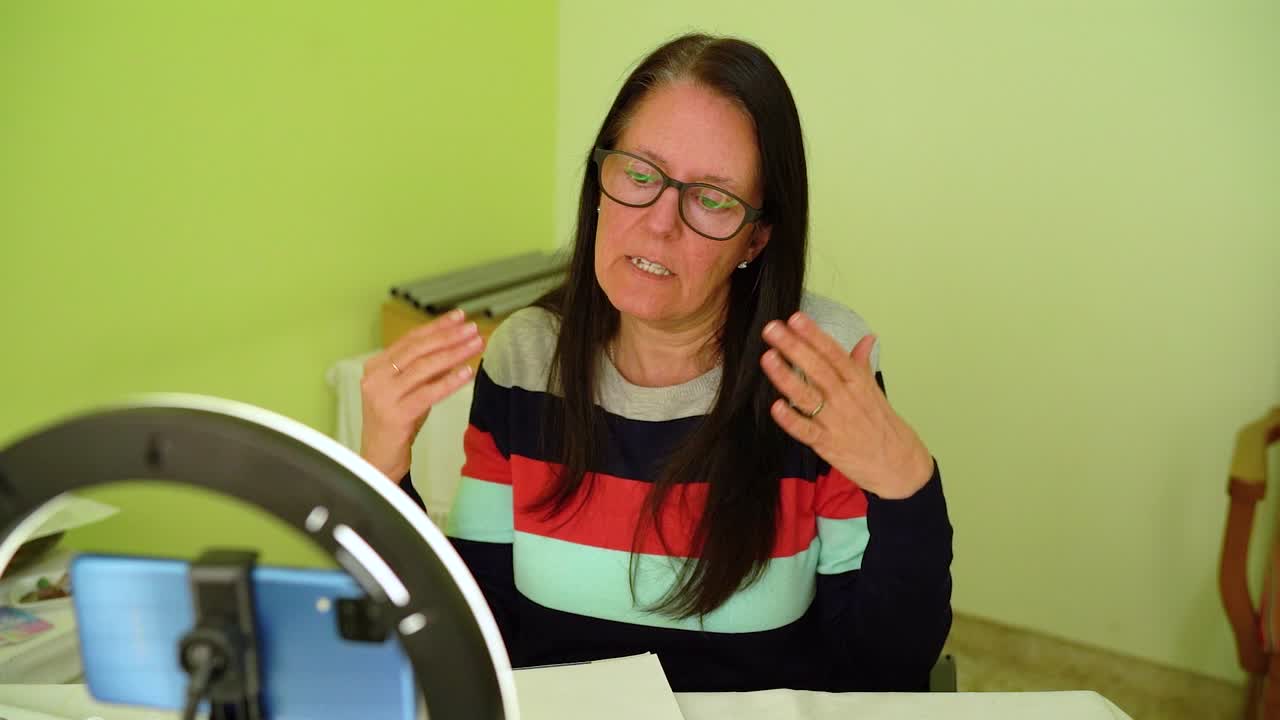 mujer adulta hablando frente a la cámara del teléfono inteligente con luz de anillo