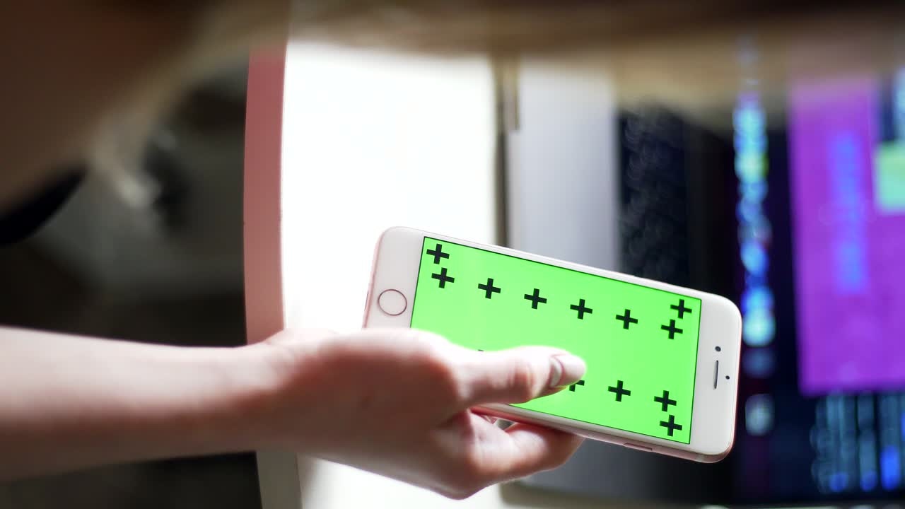 la mano de la mujer desplaza la cinta en un teléfono inteligente. pantalla verde con rastreadores