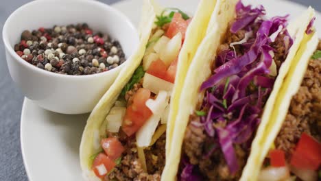 video de tacos recién preparados en un plato sobre un fondo gris