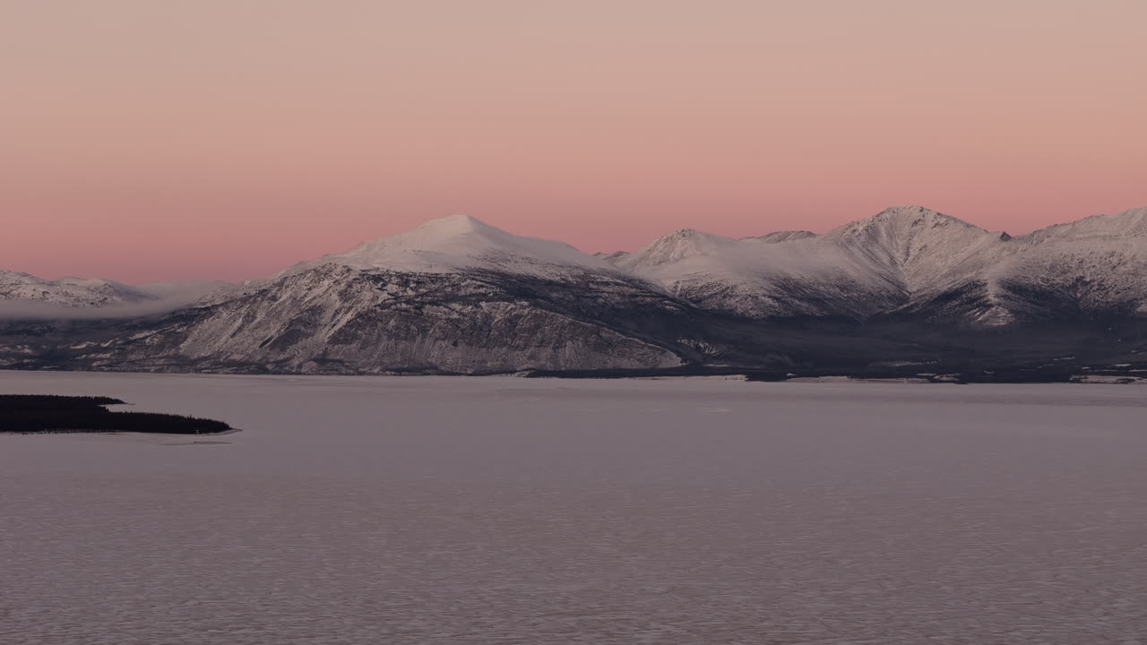 Frozen Kluane Lake And Snowy Mountain Range At Sunrise In Destruction Bay, Kluane National Park Yukon, Canada. - aerial shot