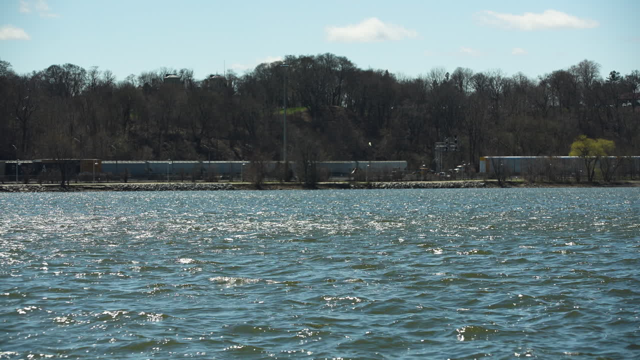 Freight Trains Along Tree-lined Shoreline Of Burlington Bay. Hamilton Harbour In Ontario, Canada. wide static shot