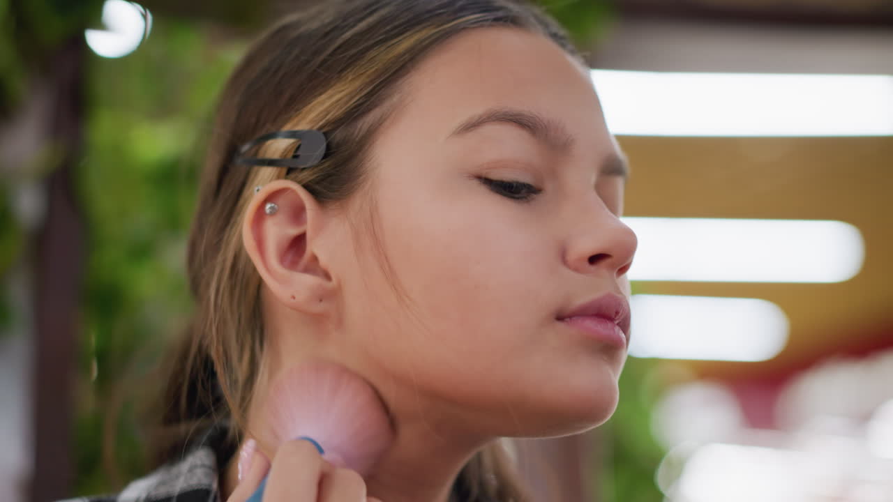 vista de primer plano de una joven aplicando maquillaje en su cuello usando un pincel de maquillaje, centrado en perfeccionar el aspecto del maquillaje, asegurando una aplicación suave y uniforme para una apariencia impecable