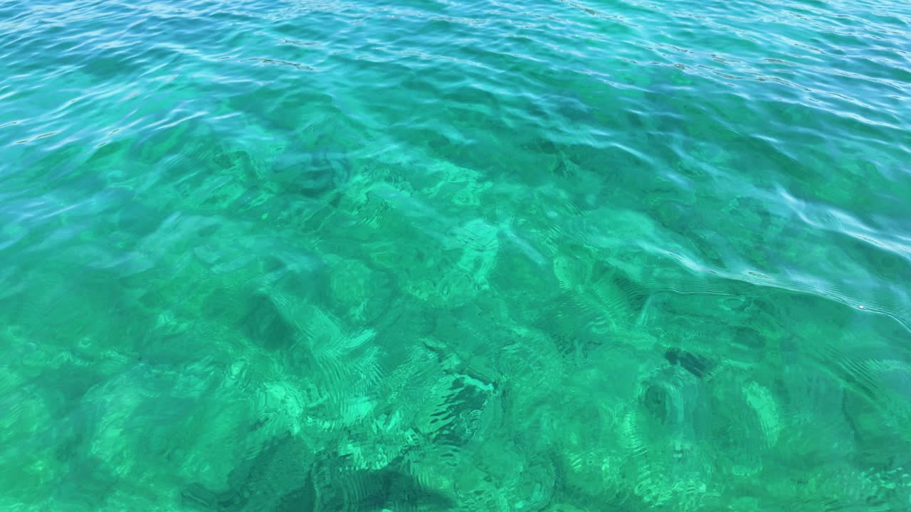 Emerald ocean sea water color texture up-close, sunshine reflection calm moving