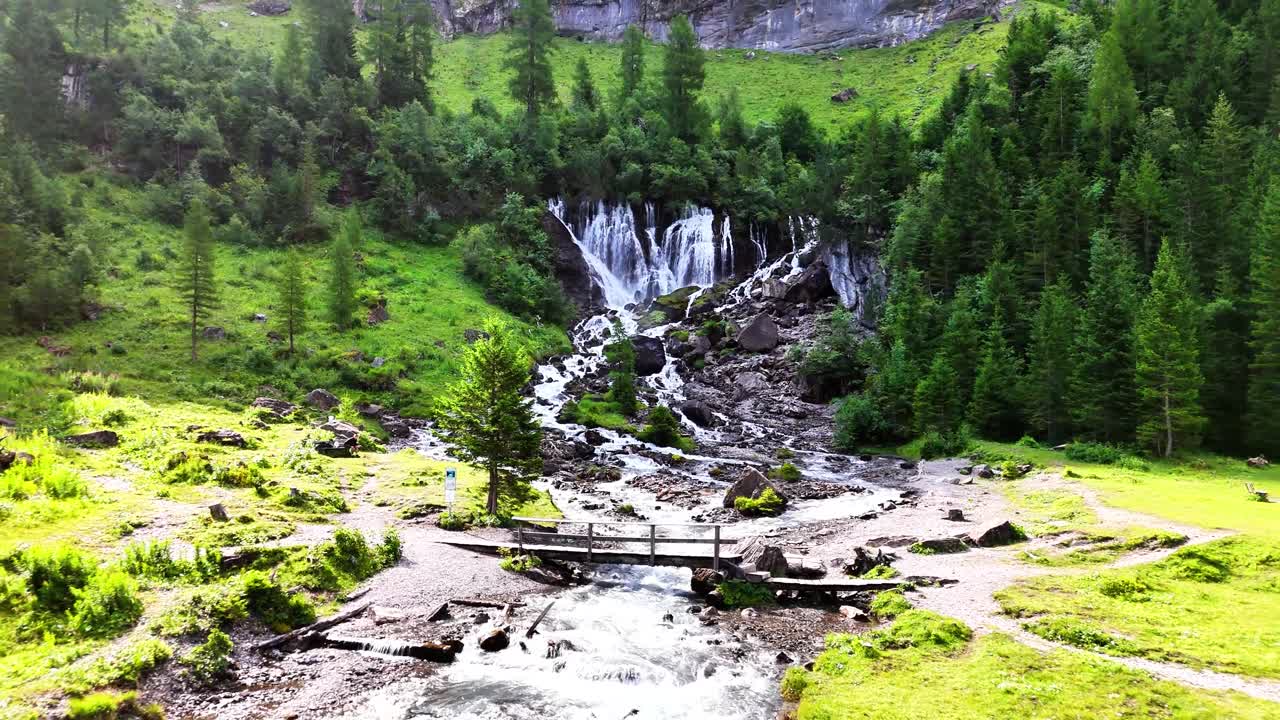 Cascata a Lenk, Sibenfälle in Svizzera con ruscelli che scorrono a cascata tra le rocce, circondata da una foresta verde, alberi alpini e un terreno coperto di muschio brillante in un ambiente di valle montana