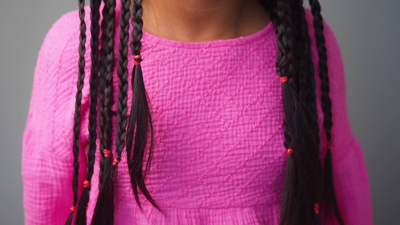 Detail Shot of Braided Hair with Red Bands on a Pink Top