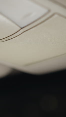 vista de una mujer abriendo una caja del techo del coche y recuperando gafas por la noche. la escena captura el momento en que su mano con uñas pintadas de negro interactúa con la caja del tejado del coche