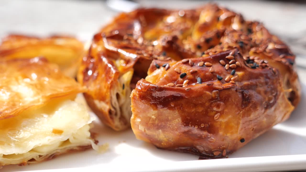Close-up of golden, flaky burek with sesame seeds