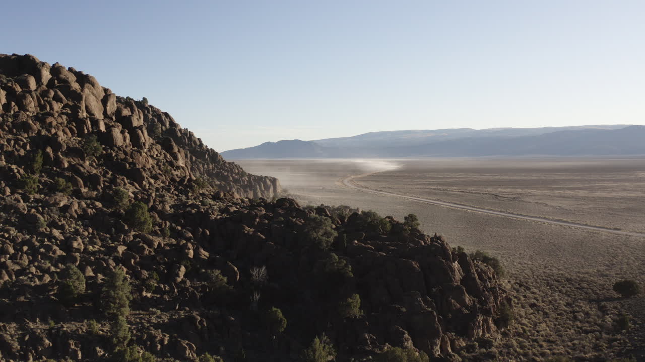 un avión no tripulado se acerca a una larga y sinuosa carretera del desierto en nevada mientras un 4x4 solitario conduce