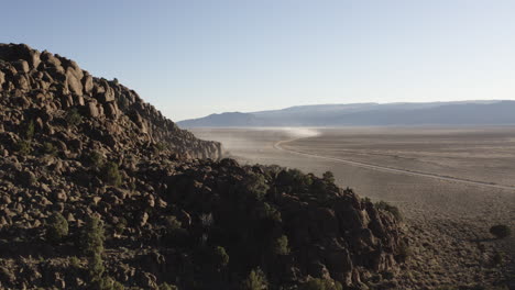 Drone-Aerial-approaching-long-winding-desert-road-in-Nevada-while-lone-4x4-drives