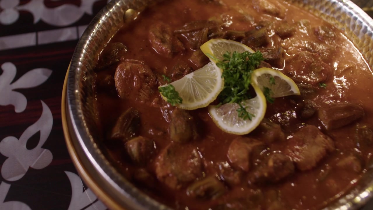 Traditional Turkish stew with meat and vegetables served in a metal pan, garnished with lemon