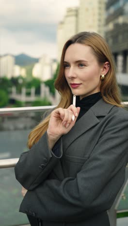 confident, focused businesswoman architect working on tablet using stylus standing at modern terrace, as the camera pushes in, she shows a hopeful, contemplative, and optimistic gaze