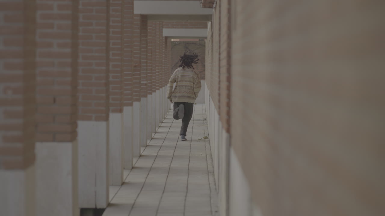 Person Running Through a Brick Corridor